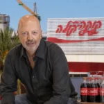 טל רבן על רקע מפעל קוקה קולה ואריזות המשקה